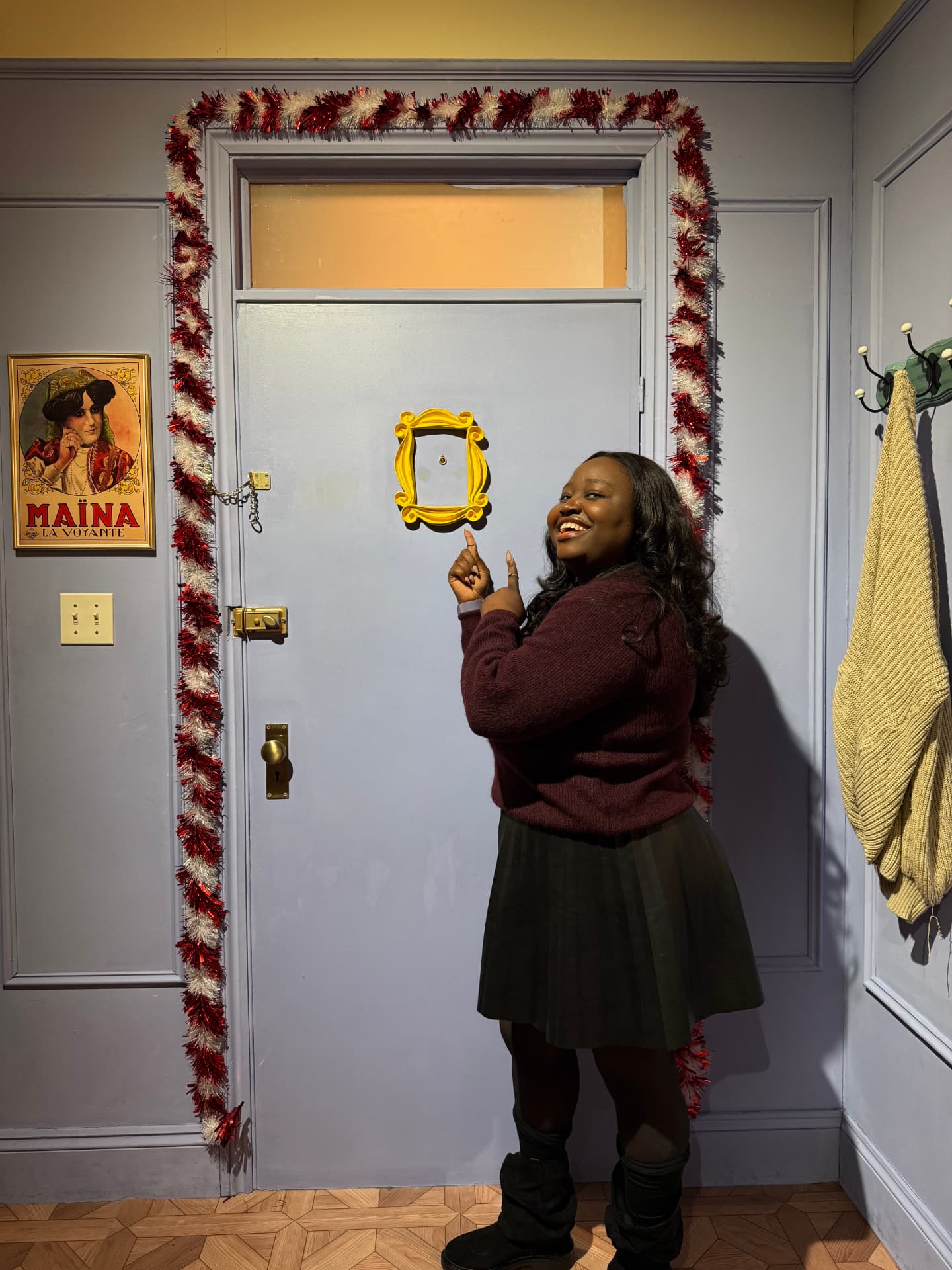 Tofunmi Balogun laughing and pointing at the yellow frame on the Friends apartment door